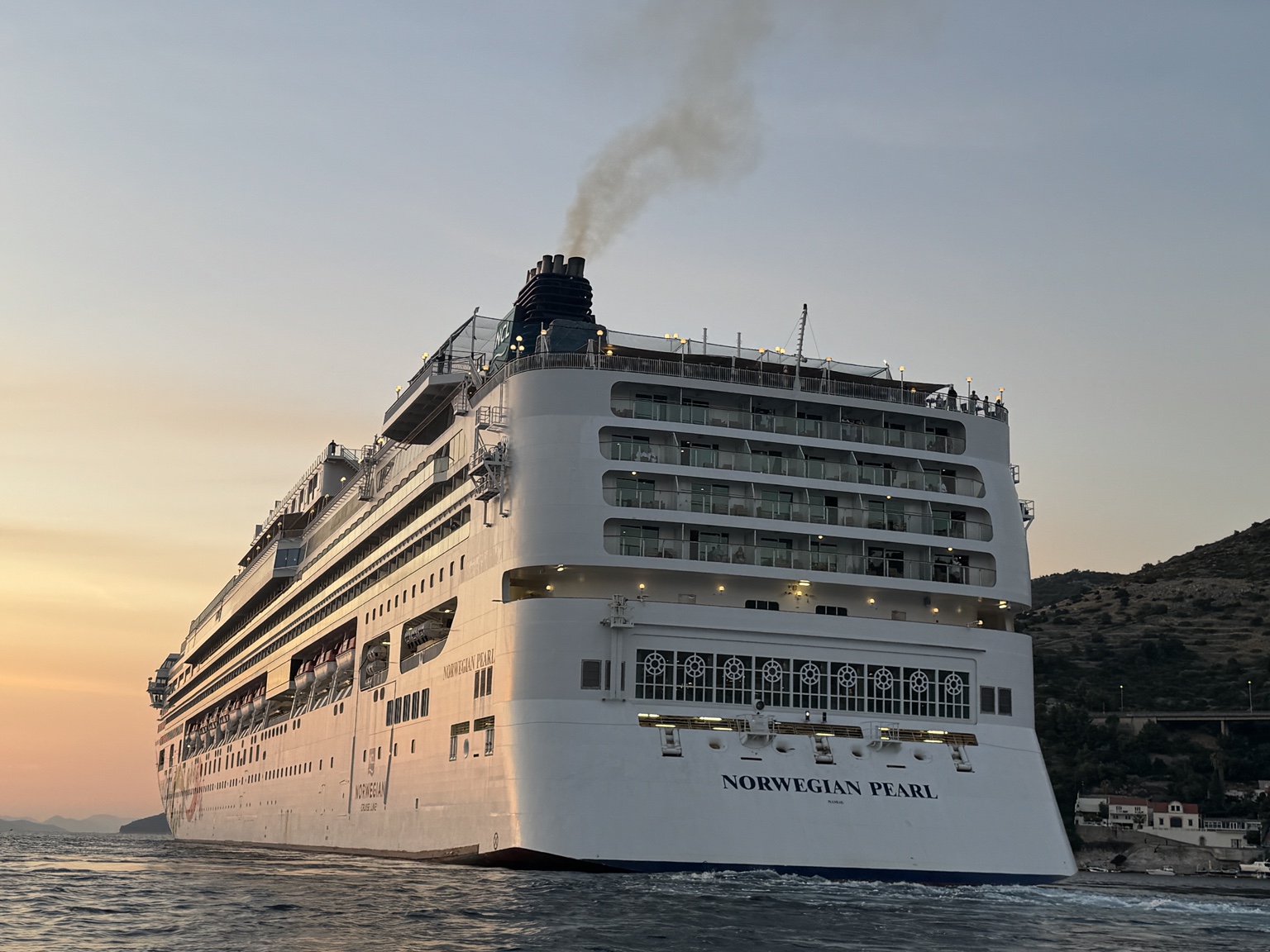 Norwegian Pearl u akvatoriju Gruža pri zalasku sunca; bliži bočni pogled na krmu. Izvorna datoteka IMG_2882.jpeg.
